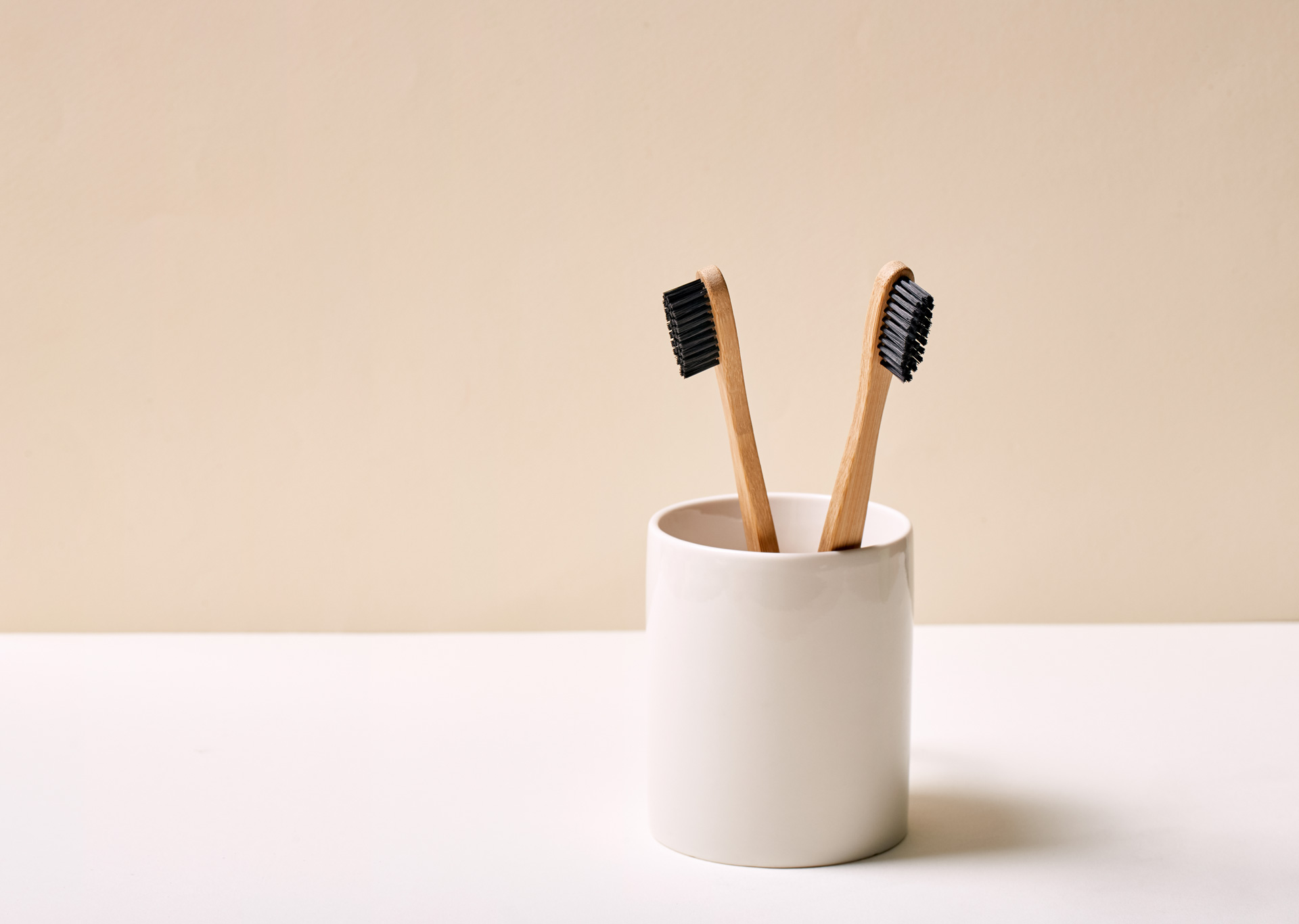 Two bamboo toothbrushes in a white holder