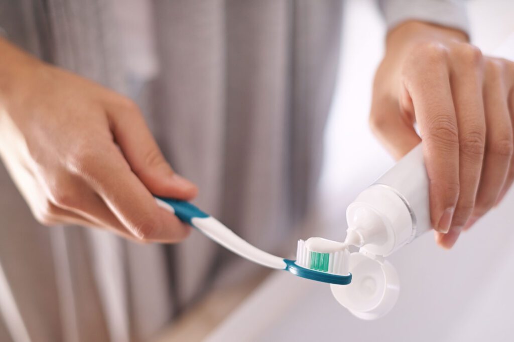 Hands putting toothpaste on toothbrush