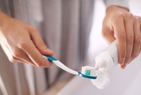 Hands putting toothpaste on toothbrush