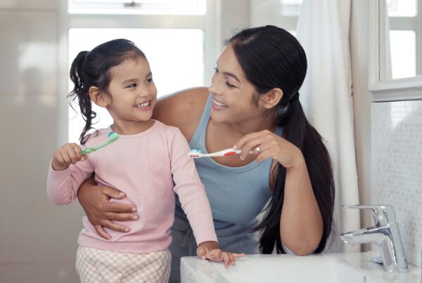 Mum and young daughter brushing teeth together